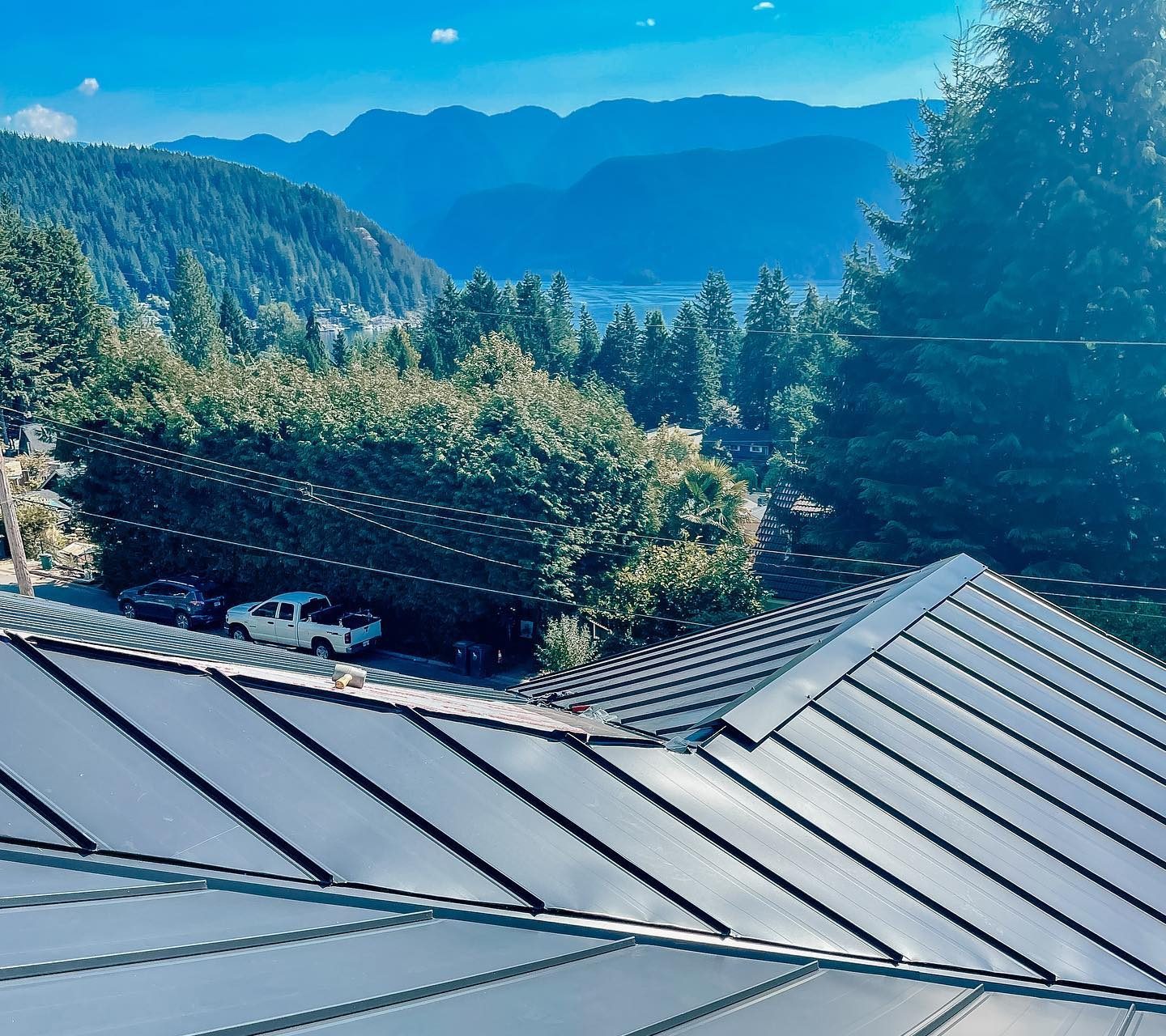 Arial view of the eaves of a metal roof with forest and ocean views in the background