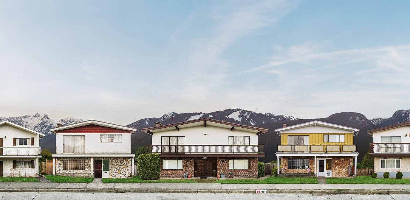 A row of 5 Vancouver Special homes with the North Shore mountains in the background