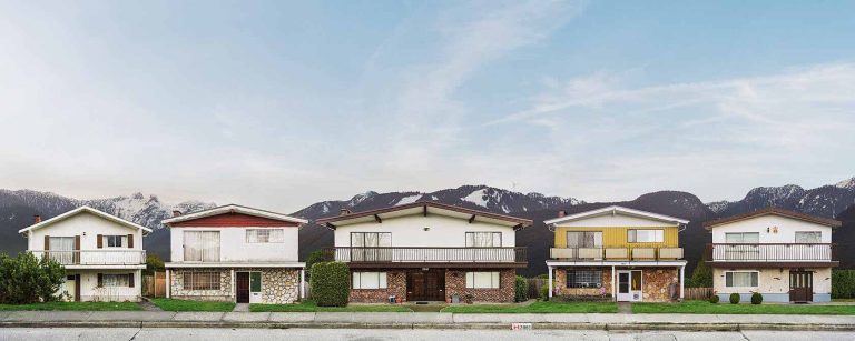 A row of 3 Vancouver Special homes with the North Shore mountains in the background